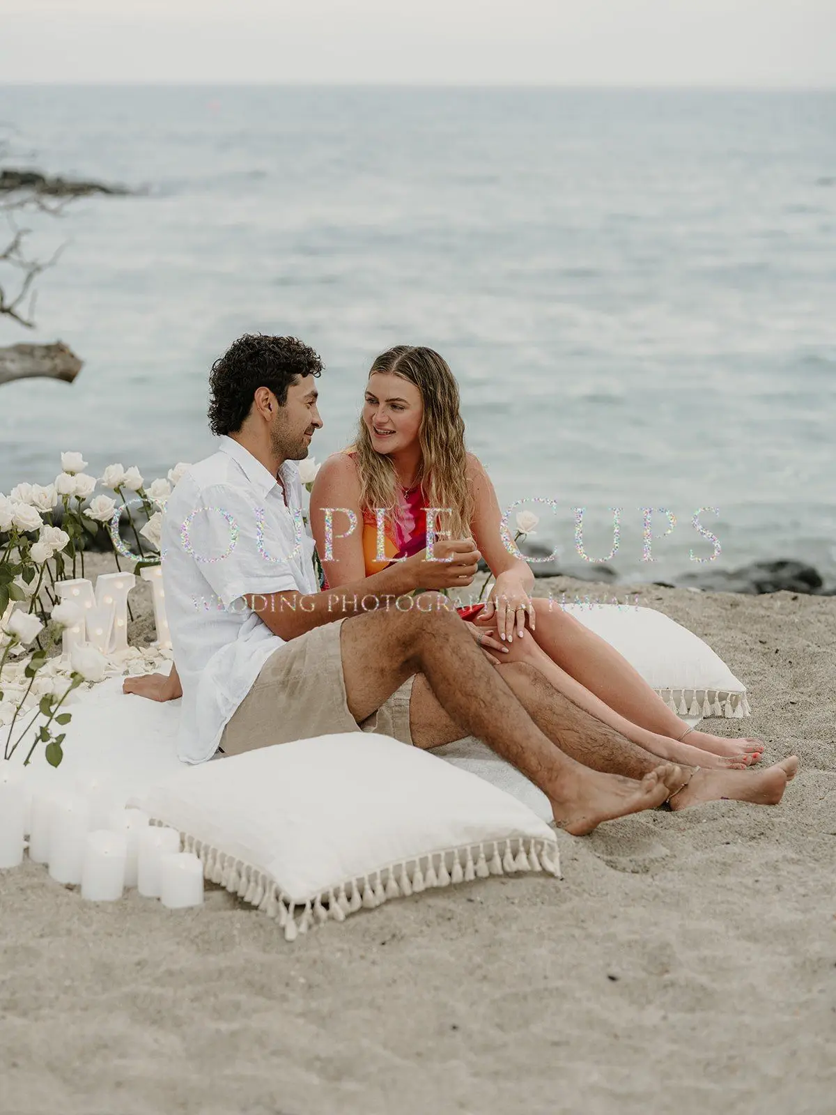 A newly engaged couple relaxes together at a beach picnic on the Big Island